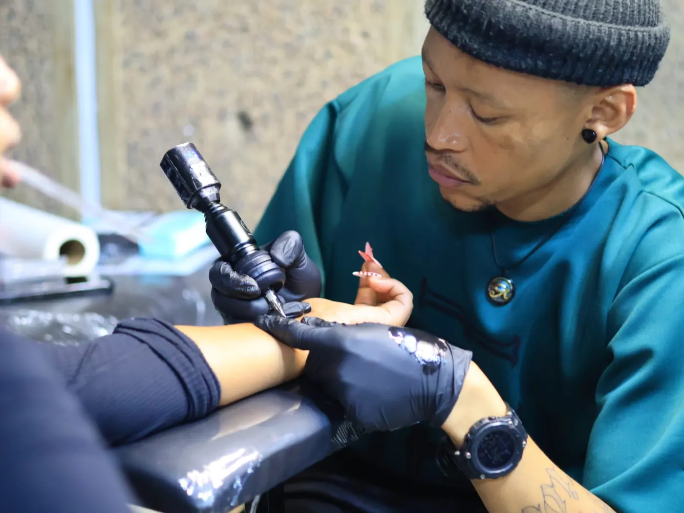 Payne tattooing a client's forearm